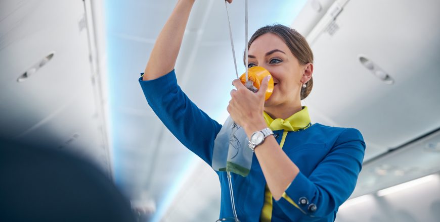 Air hostess showing how to use an oxygen mask on board