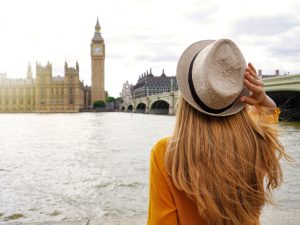 Tourism in London. Back view of tourist woman enjoying sight of Westminster palace and bridge on Thames with famous Big Ben tower in London, UK.