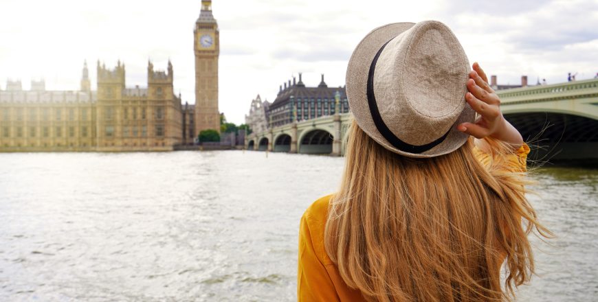 Tourism in London. Back view of tourist woman enjoying sight of Westminster palace and bridge on Thames with famous Big Ben tower in London, UK.